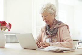 Woman in a bright room, focused on her laptop